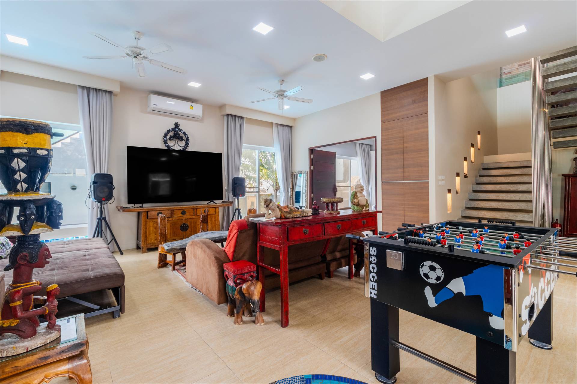 Entertainment lounge with flat-screen TV, foosball table, and Thai decor