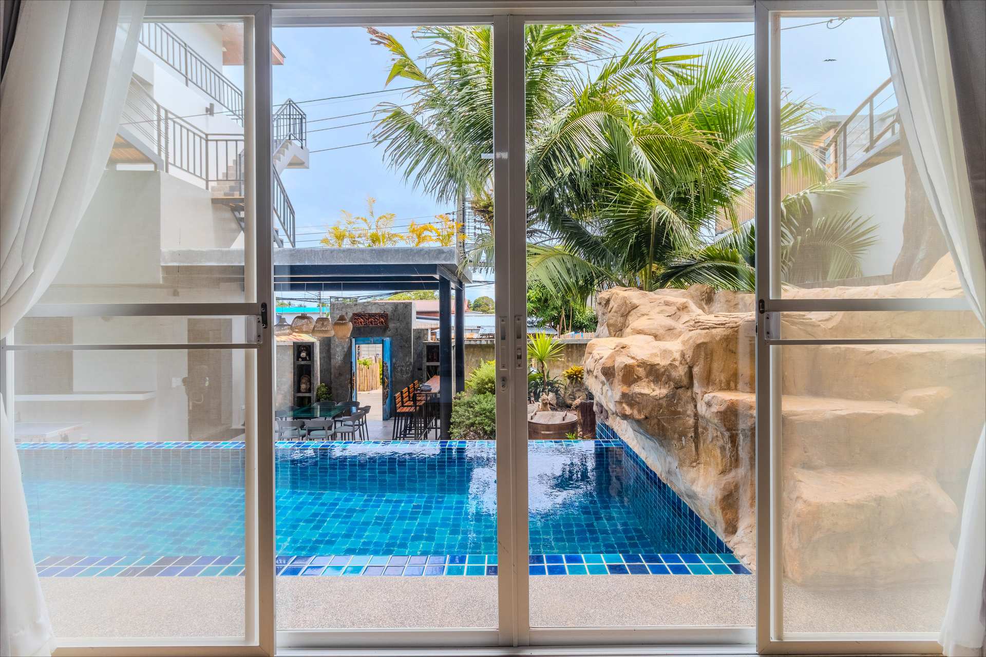 Poolside terrace with outdoor living area, comfortable seating, and views across the estate grounds