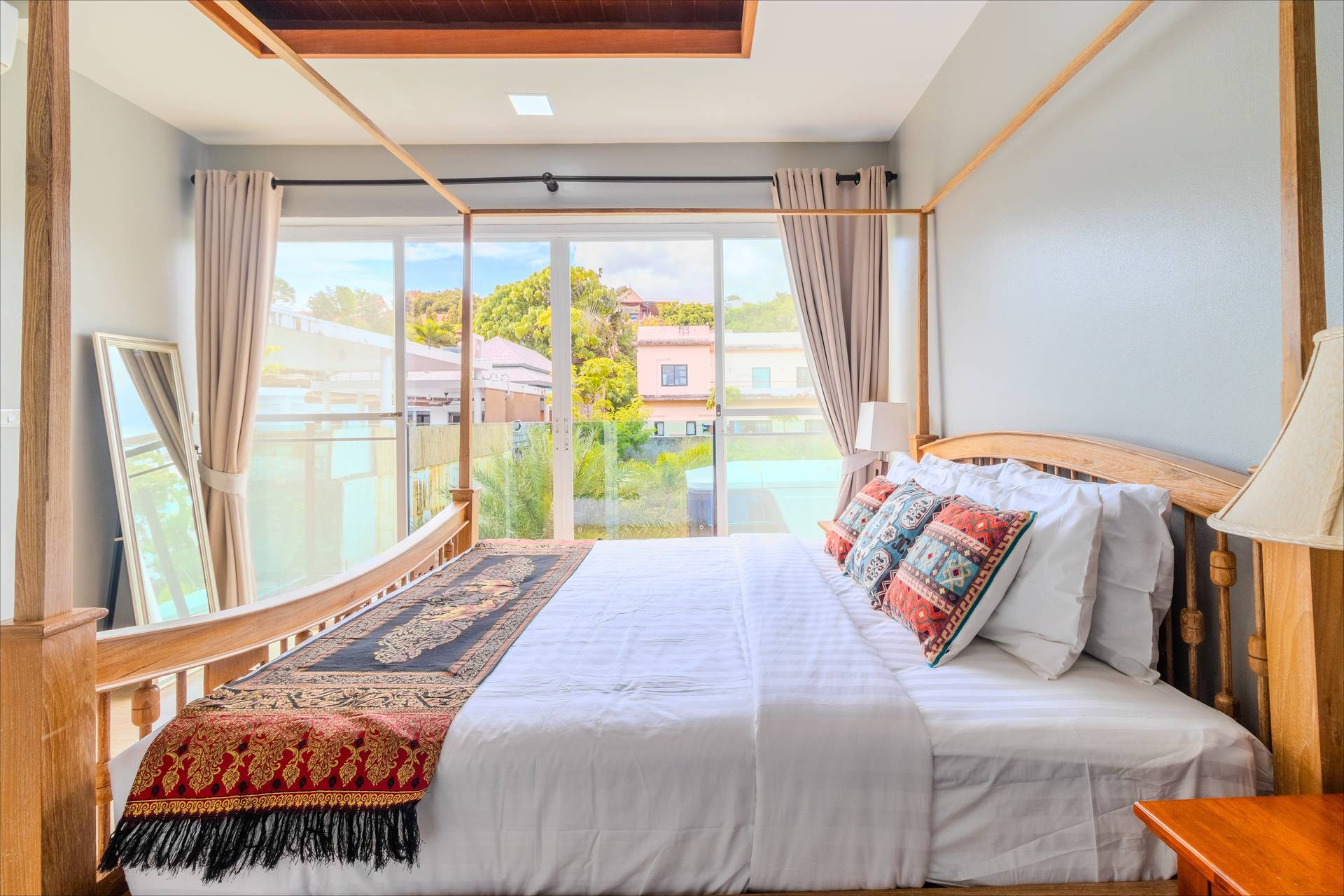 Four-poster teak bed with Thai silk runner and pool-view balcony