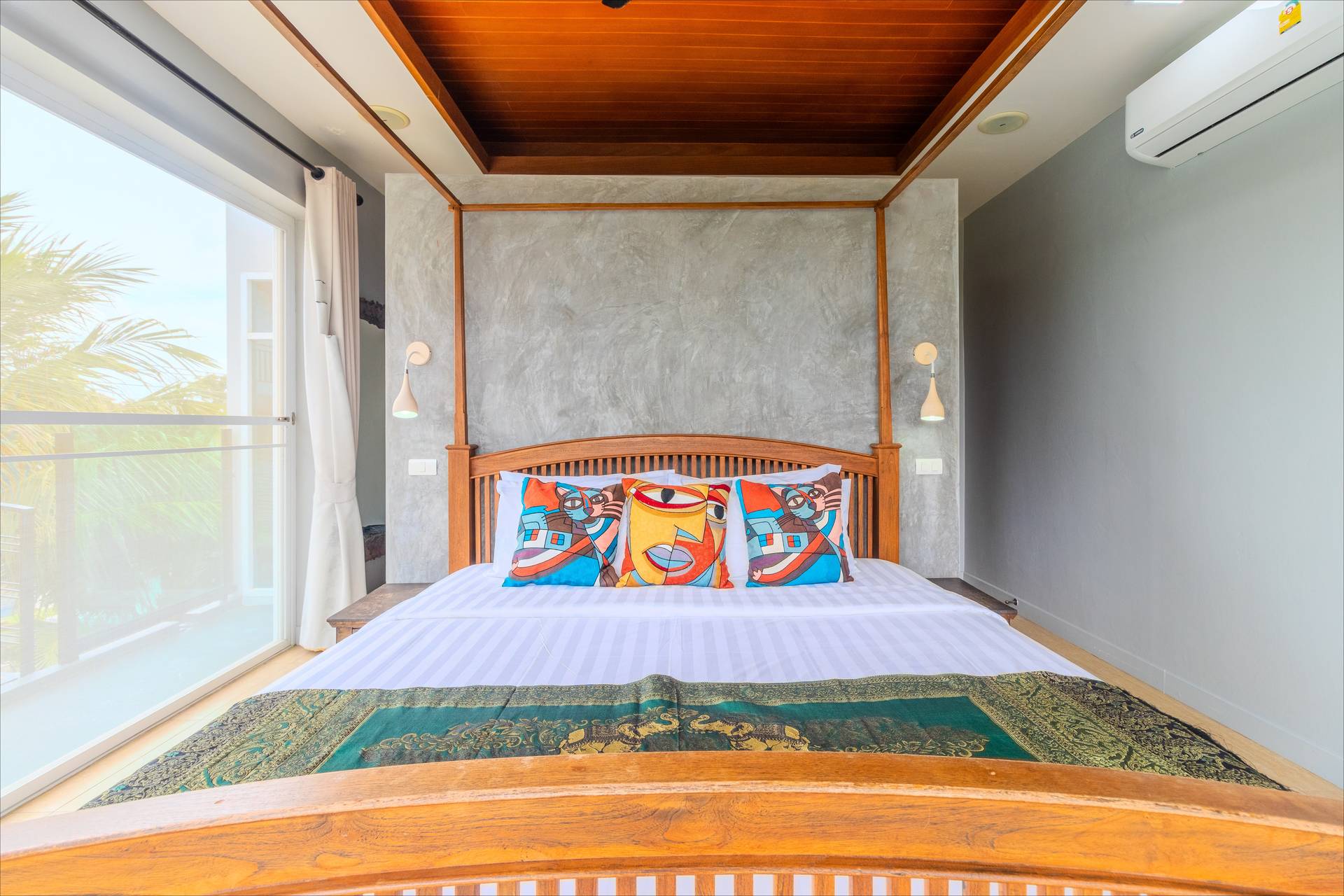 Teak four-poster bed with concrete feature wall and balcony palm views
