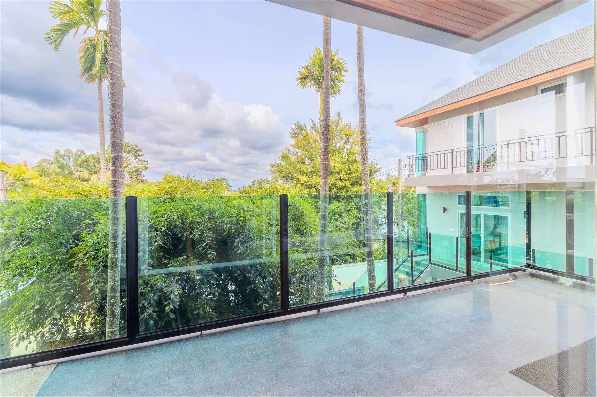 Glass-railed upper terrace overlooking tropical gardens and pool area