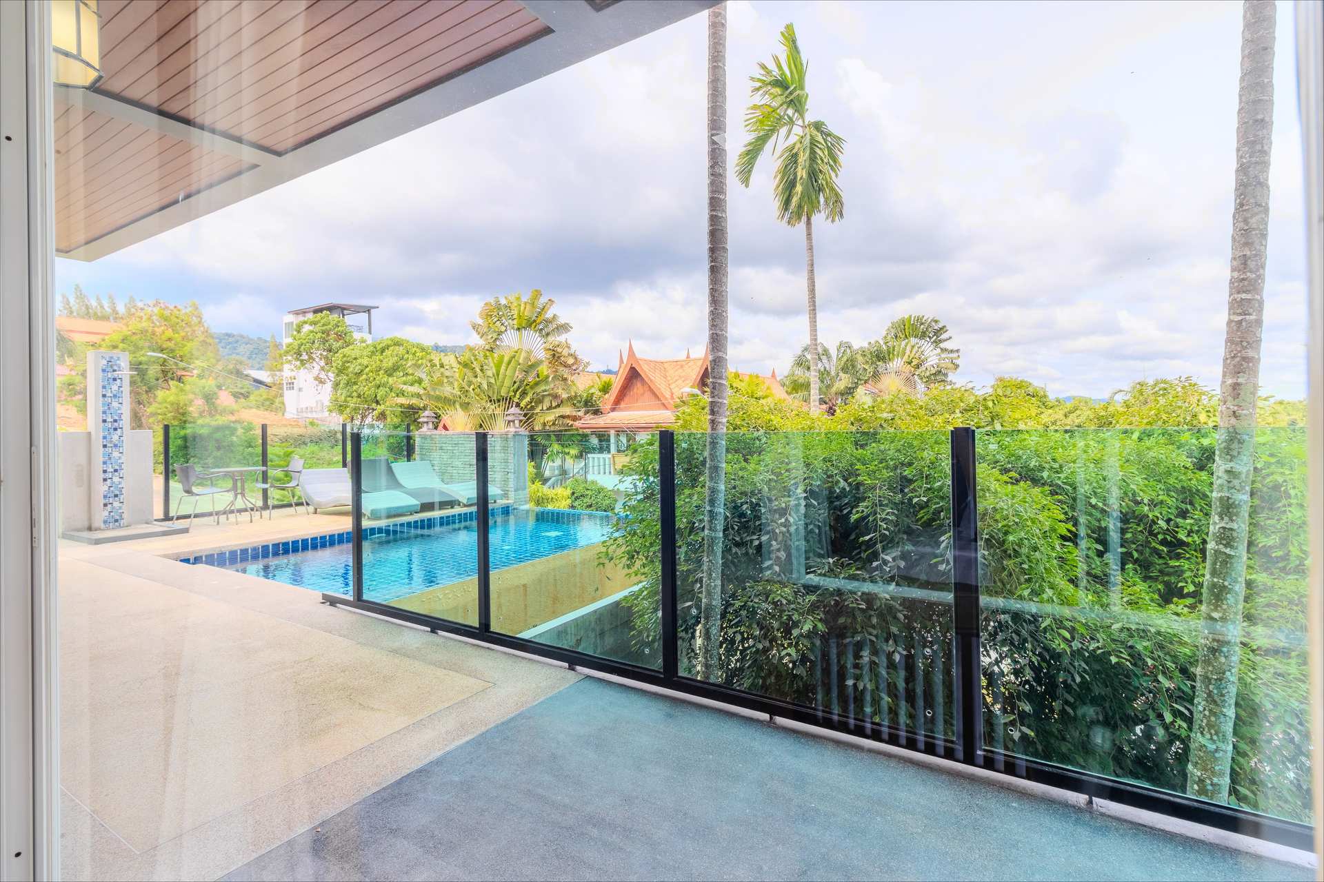 Rooftop infinity pool with sun loungers and Thai temple rooftop backdrop