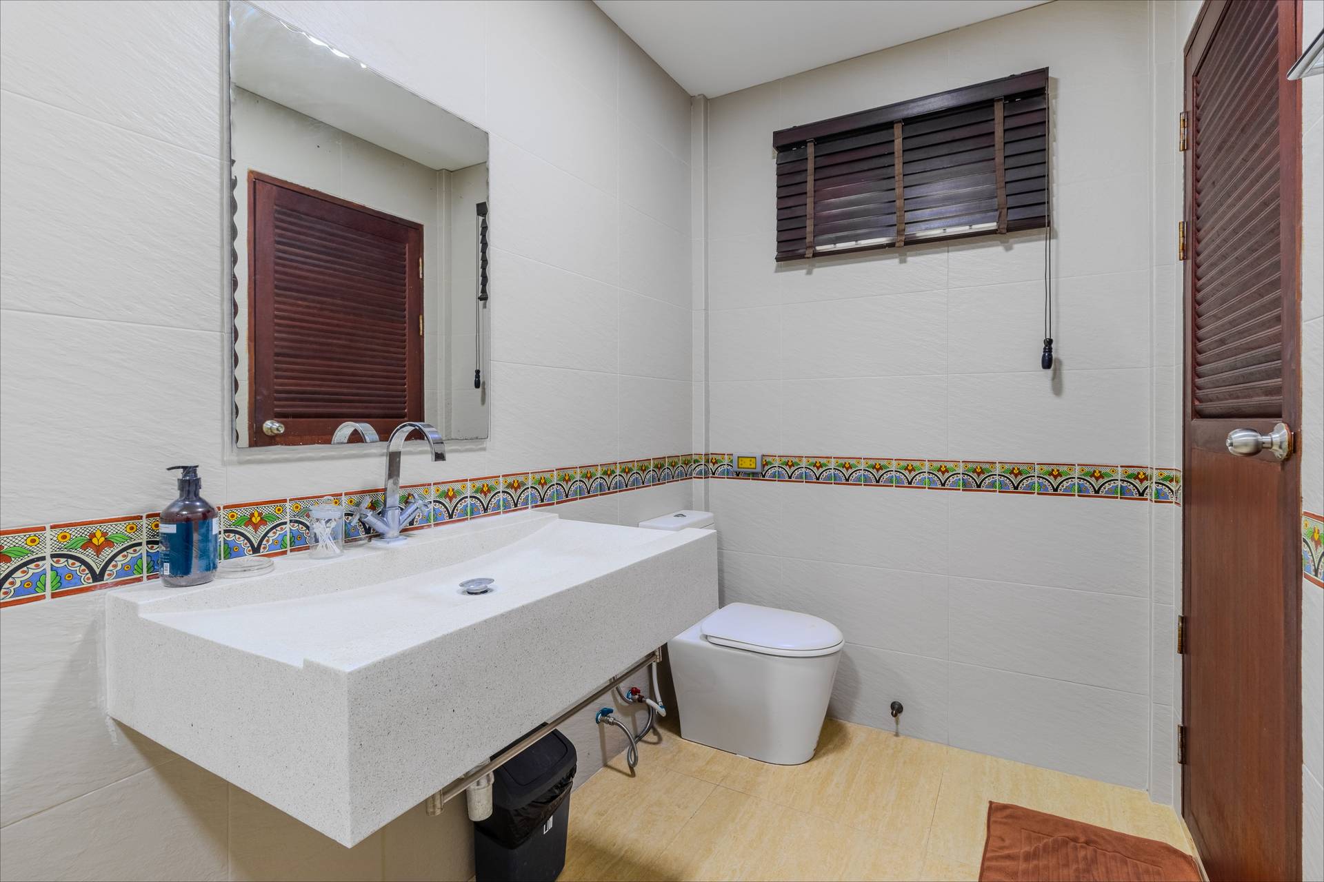 Modern en-suite with decorative tile border and stone vanity
