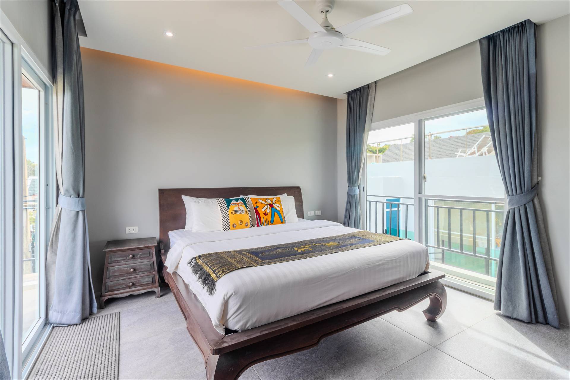 Premium bedroom suite featuring private balcony overlooking the tropical estate grounds and pool area