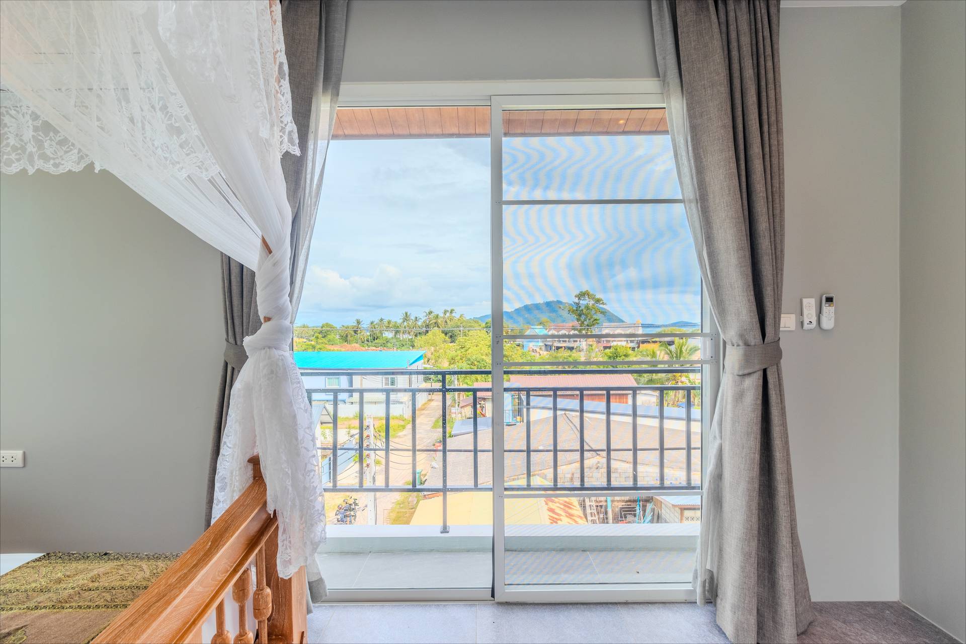 Bedroom balcony view of Rawai hills through floor-to-ceiling sliding doors