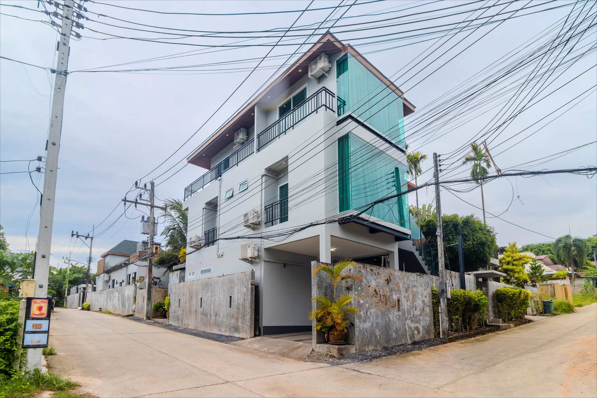 Street view of modern three-storey luxury villa with turquoise glass balconies