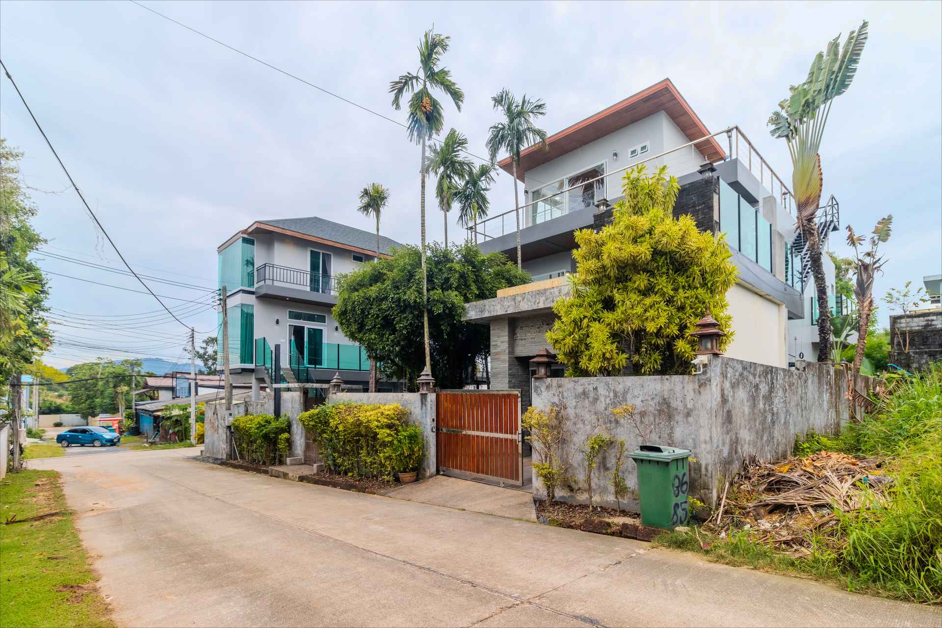 Front facade of villa complex with tropical landscaping and gated entrance