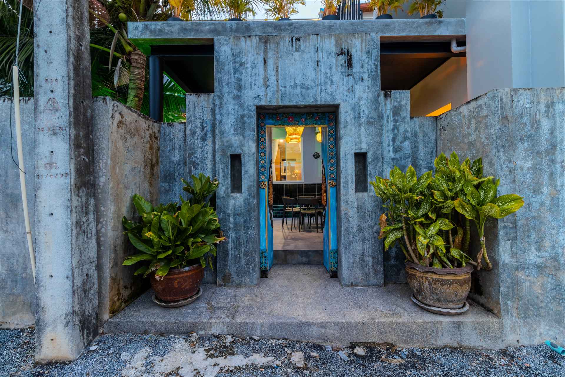 Concrete garden entrance with turquoise door and potted plants