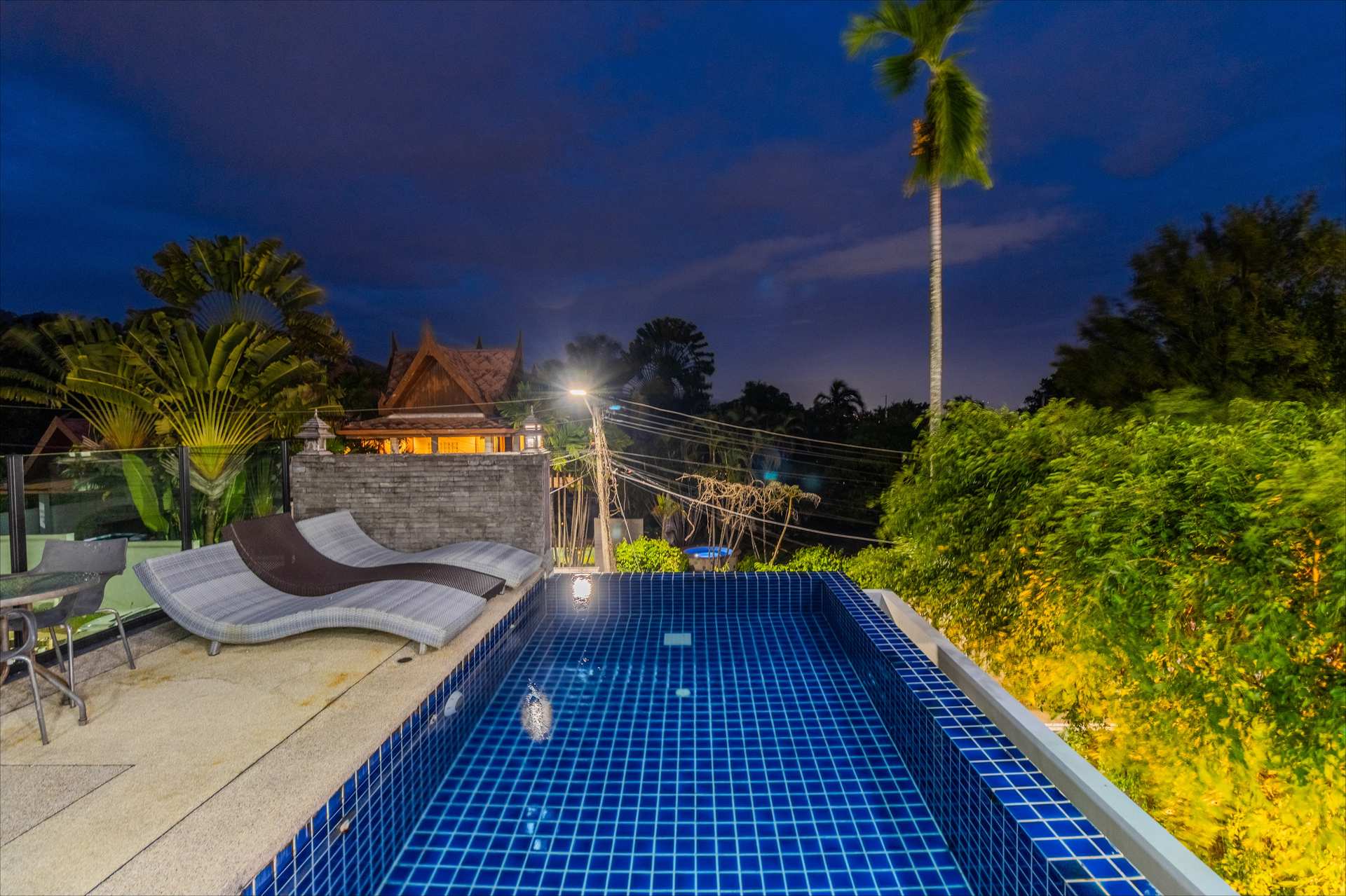 Upper-level walkway overlooking villa courtyard and pool at dusk